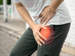Osoba aktywna z bólem uda, wskazująca miejsce dolegliwości
