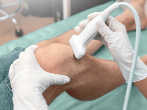 USG narządu ruchu — lekarz przykłada głowicę USG do kolana pacjenta.