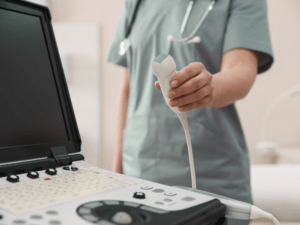 Badanie USG w gabinecie — lekarz trzyma głowicę obok aparatu ultrasonograficznego.