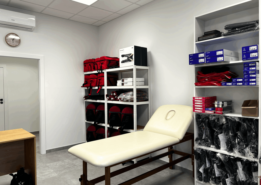 Wnętrze sklepu medycznego i wypożyczalni sprzętu JJClinic z kozetką i szafą ze sprzętem rehabilitacyjnym do wypożyczenia