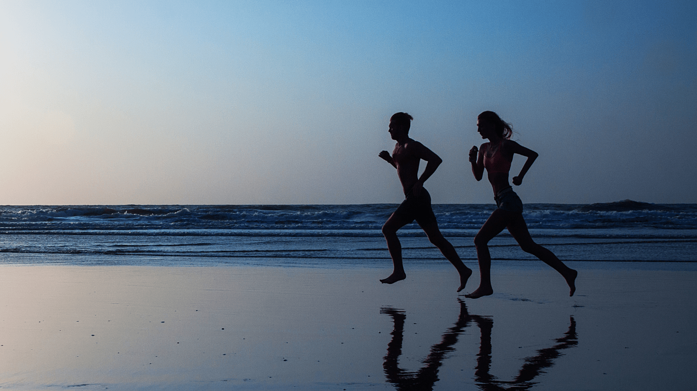 Aktywna para biegnąca po plaży – ruch i aktywność fizyczna wspierające zdrowie stawów