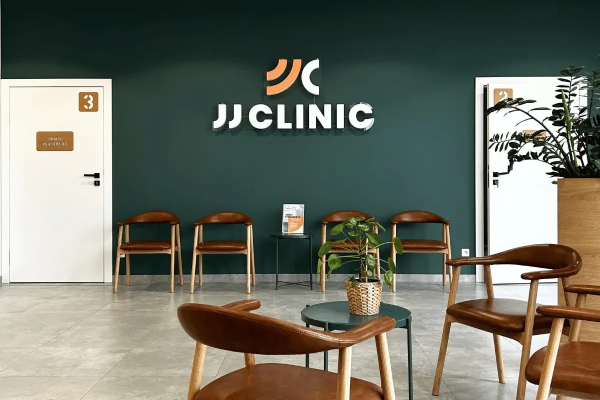 Poczekalnia kliniki ortopedycznej JJClinic – zielona ściana z neonem logo oraz wygodna strefa oczekiwania dla pacjentów