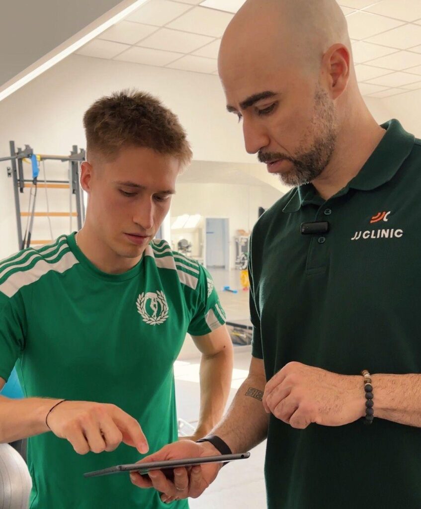 Trener Daniel Barbosa omawia z piłkarzem wyniki testów funkcjonalnych na iPadzie w JJClinic.