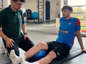 Pacjent wykonuje ćwiczenie kolana z piłką podczas pierwszej rehabilitacji po rekonstrukcji ACL pod nadzorem fizjoterapeuty Damiana Słowińskiego