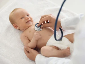 neonatolog bada niemowlaka na kozetce