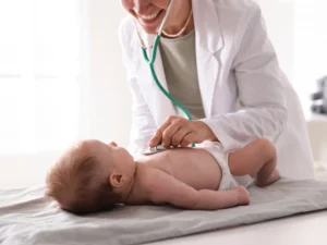neonatolog osłuchuje niemowlaka na kozetce w gabinecie