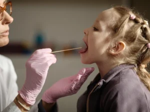 pediatra badająca gardło dziecka za pomocą szpatułki laryngologicznej.