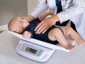 neonatolog waży niemowlaka w gabinecie